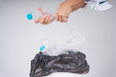 Kadın plastik şişeyi geri dönüşüm kutusuna koymadan önce döndürür..