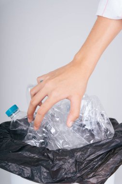 Kadın eli plastik şişeyi tekrar açtırıyor ya da çöp kutusuna geri dönüştürüyor..