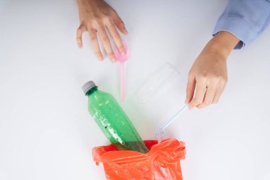 Kadın elleri plastik atıkları geri dönüşüm için plastik bir torbaya koyuyor..
