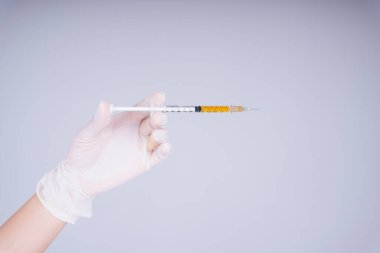 Doktor elinde şırınga aşısı tutan beyaz eldivenler giyiyor. Beyaz arka planda izole edilmiş..