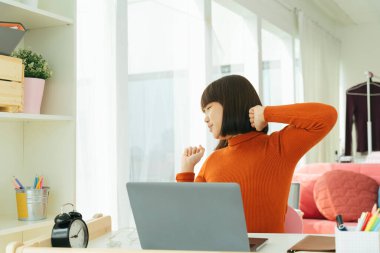 Güzel genç Asyalı Taylandlı siyah kısa saçlı kadın evde öğrendikten sonra kollarını uzatıyor..