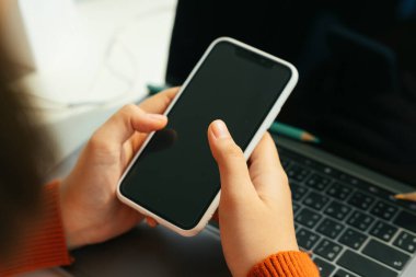 Akıllı telefon ve dizüstü bilgisayarla evden öğrenci çalışması.