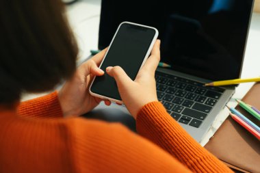 Akıllı telefon ve dizüstü bilgisayarla evden öğrenci çalışması.