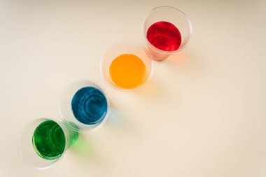 Üst manzara - tatlı gökkuşağı soda, fotokopi alanı olan plastik bardakta köpüklü su. Yeşil. Mavi. Turuncu. Kırmızı.