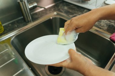 Mutfak lavabosunda bulaşıkları süngerle yıka. Covid-19 Coronavirus önleme.