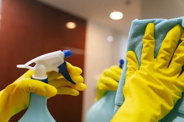 Tuvalette deterjan şişesi ve bez temizleme aynası kullanan bir temizlikçi. Covid-19 Coronavirus önleme.