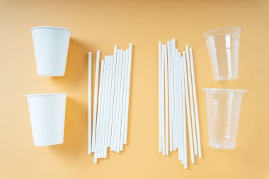 Tek kullanımlık plastik bardak ve turuncu arka planda saman.