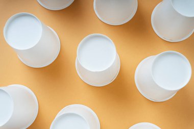 Turuncu zemin üzerinde kare şeklinde dokuz kağıt bardak ters çevrilmiş..