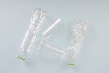 Plastik atık. Beyaz arka planda şeffaf şişe ve fincanlar.