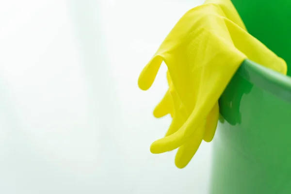 Green pail water bucket and yellow gloves over white background. Copy space.