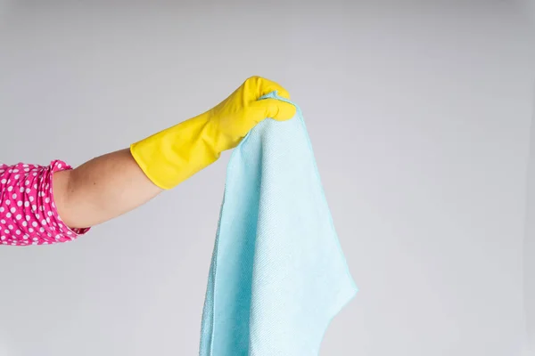 Cleaner hand wearing yellow protective glove holding blue rag cloth isolate over white background. Covid-19 Coronavirus prevention.