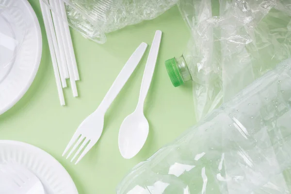 Top view - Plastic waste rubbish over green background.