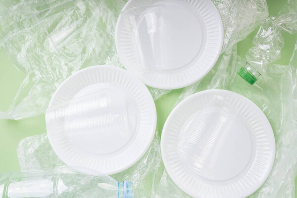 Top view - Plastic waste rubbish over green background.