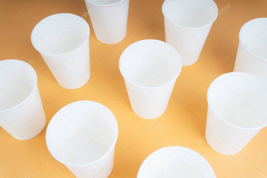 Empty nine paper cups on orange beige table.