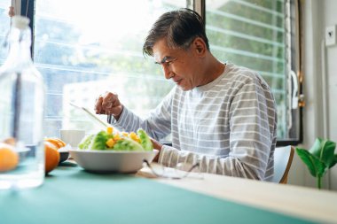 Mutlu yaşlı adam kahvaltısını yaparken çocuğu ve torunuyla görüntülü konuşma yapıyor..