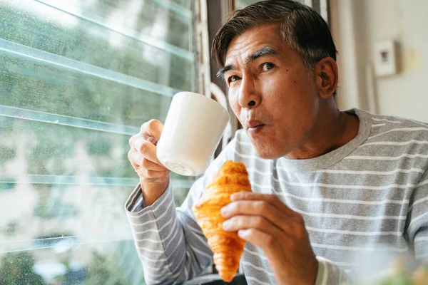 Velho Bebe Café Quente Xícara Enquanto Ele Segura Croissant Salsicha — Fotografia de Stock