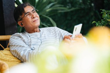 Yaşlı adam güzel bir havada gökyüzüne bakarken mobil uygulamadan müziği dinle..