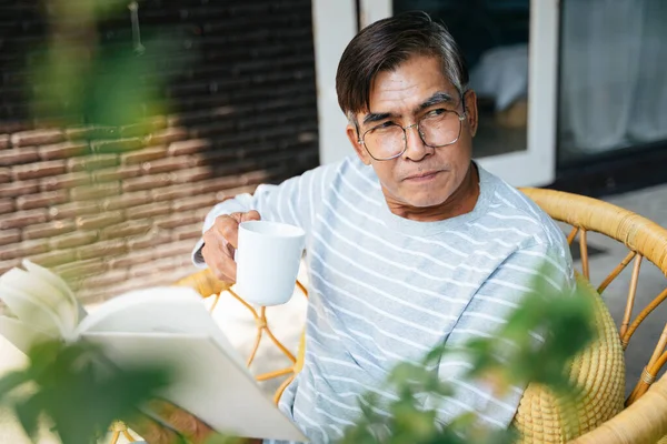 Glücklicher Alter Mann Sitzt Auf Korbstuhl Seinem Garten Und Hält — Stockfoto