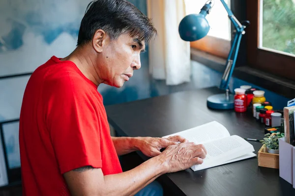 Homem Velho Camiseta Vermelha Lendo Livro Mesa Madeira Lado Janela — Fotografia de Stock