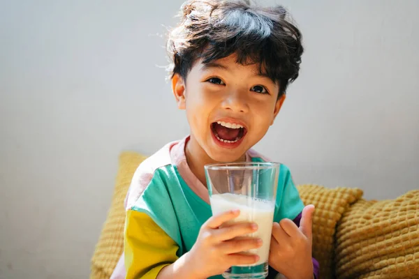 Küçük çocuk, temiz bardakta mutlulukla süt içmenin tadını çıkar..