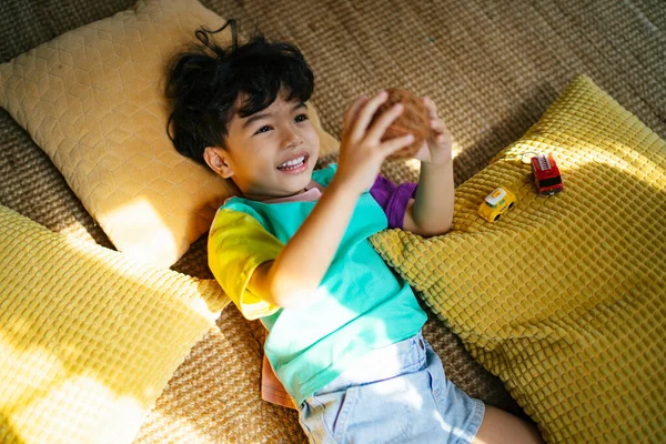 Anak Kecil Berbaring Lantai Dengan Banyak Pilloe Memainkan Mainan Bawah — Stok Foto