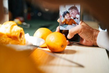 Büyükbaba ve torun, kahvaltıda selfie çekerken akıllı telefonun kamerasında..