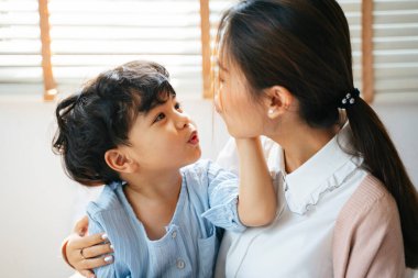 Küçük çocuk annesinin kucağına uzandı ve annesinin yüzüne sevgiyle dokundu..