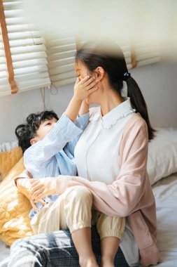 Küçük çocuk annesinin kucağına uzandı ve annesinin yüzüne sevgiyle dokundu..