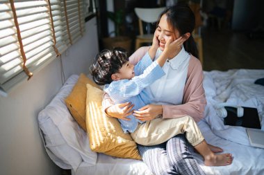 Küçük çocuk annesinin kucağına uzandı ve annesinin yüzüne sevgiyle dokundu..