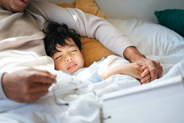 Cropped image of little boy sleeping at daytime in his grandpa\'s arm.