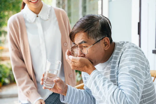 白髪の老人が私立の看護師から薬を飲んで水を飲む — ストック写真