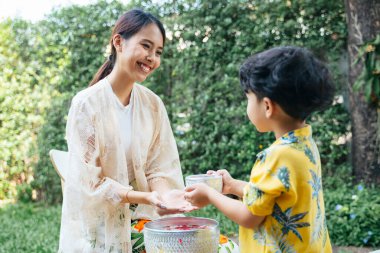 Annesi oğlunun başını nazikçe ovalarken o geleneksel bir günde eline çiçek suyu dökerdi..