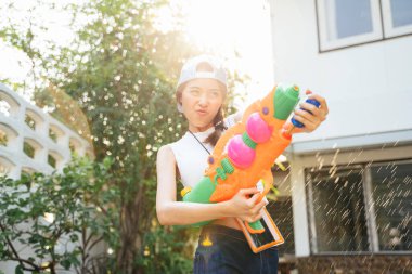 Songkran gününde güzel bir kadın su tabancasıyla suya su sıçratmış, su ve baloncuk sıçratmış..