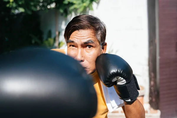 Old man get the boxing traning by himself at his house in sunny day.
