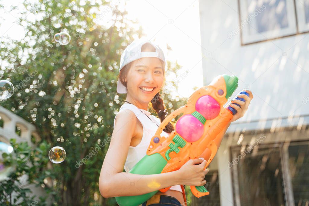 Beautigul woman splash the water with water gun in Songkran day, splashed water and bubble.