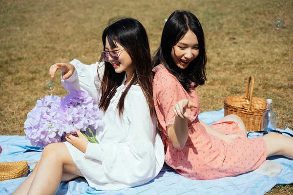 Dwie Dziewczyny Siedzące Tyłu Macie Boisku Grające Bąbelki Fioletowe Kwiaty — Zdjęcie stockowe