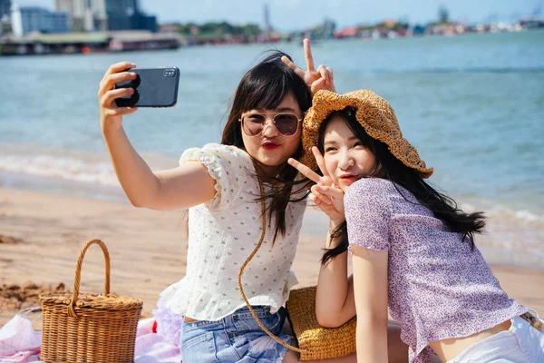 Duas Meninas Sentadas Praia Mar Dia Ensolarado Tirar Uma Selfie — Fotografia de Stock