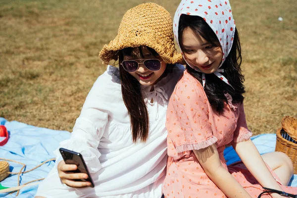 Two Girls Sitting Field Watching Photo Trip Smartphone — Stock Photo, Image