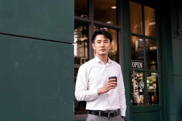 Adult asian thai businessman on white shirt holding a cup of coffee.