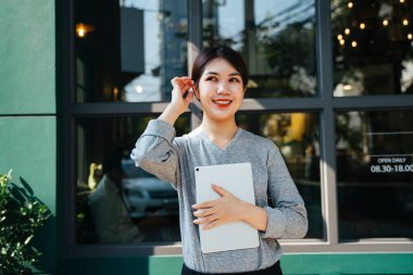 Kafe arka planında tablet tutan zarif genç bir iş kadını..