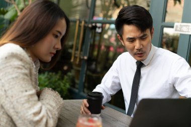 Genç Asyalı iş adamları birlikte çalışıp laptoptaki sunuma bakıyorlar..