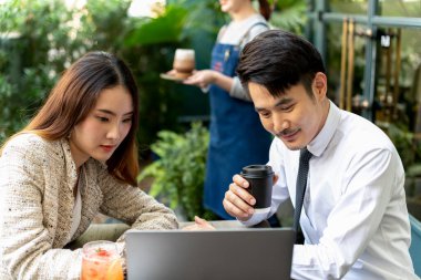 Asyalı işadamları ortak olarak kahve dükkanında bilgisayar bakıyorlar..