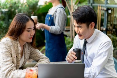 Asyalı işadamları ortak olarak kahve dükkanında bilgisayar bakıyorlar..