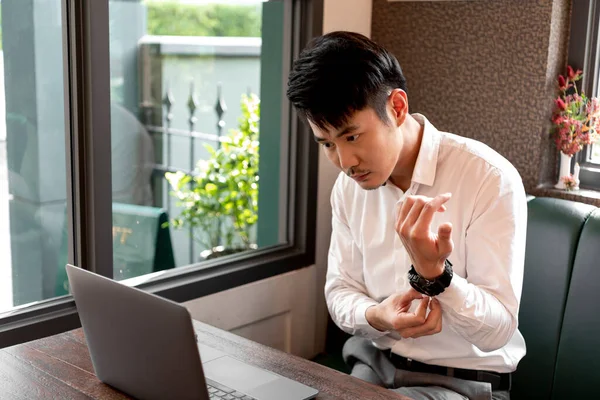 富有洞察力的亚裔泰国人商人穿着白衬衫 在咖啡店的笔记本电脑上工作 在户外工作 调整手表 — 图库照片