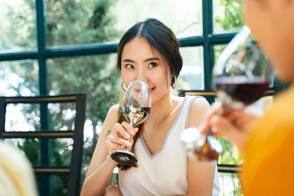 Beautiful asian woman sipping the wine from glass, smiling to the man next to her.