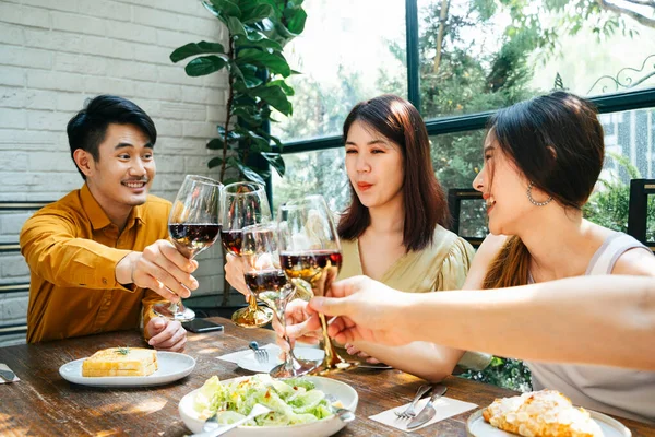 Three asian people toasting with glasses of wine. Celebration party. People cheers with wine to celebrate. Having meal at restaurant.