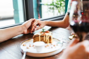 Tatlı Kafe 'de el ele tutuşan romantik çiftin yakın eli. Bir kadeh şarap tutarken.