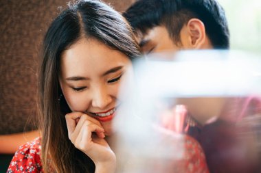 Restoranda öpüşen Asyalı romantik çiftin yüzünü kapatın. Ön planda şarap kadehi.