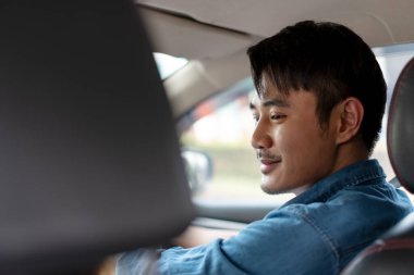 Kot pantolon giyen, yolda araba süren neşeli, yakışıklı Asyalı Taylandlı adam..