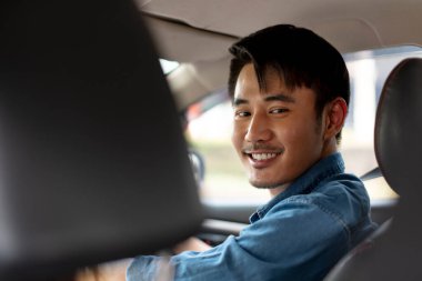 Kot pantolon giyen, yolda araba süren neşeli, yakışıklı Asyalı Taylandlı adam..